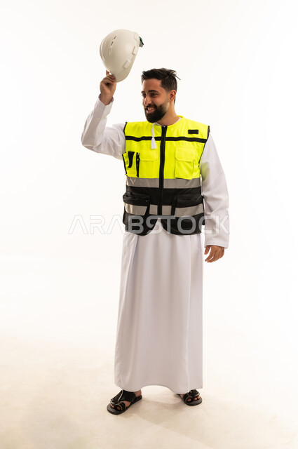 مهندس سعودي يرتدي سترة عاكسة ويحمل خوذة السلامة
