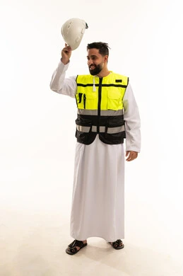 مهندس سعودي يرتدي سترة عاكسة ويحمل خوذة السلامة