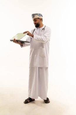 طبيب عماني يحمل كمبيوتر محمول على خلفية بيضاء