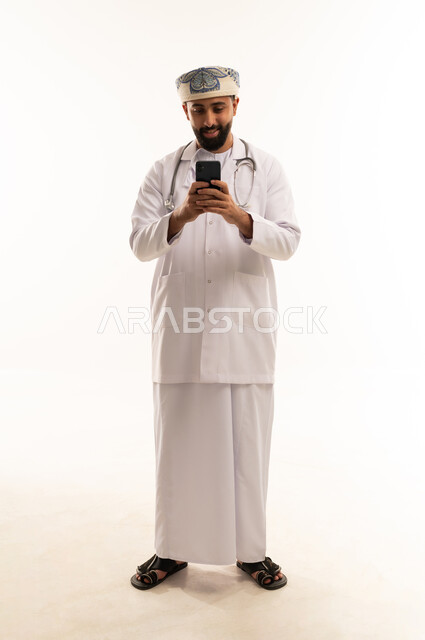 طبيب عماني يستخدم هاتفاً ذكياً على خلفية بيضاء