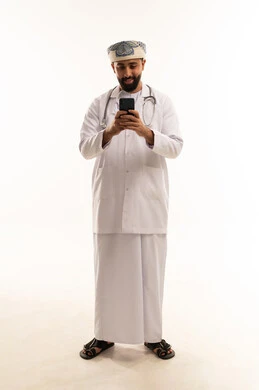 طبيب عماني يستخدم هاتفاً ذكياً على خلفية بيضاء