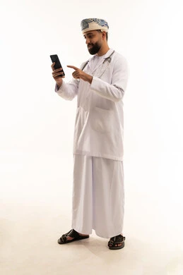 طبيب عُماني مهني يستخدم الهاتف الذكي بخلفية بيضاء طبيب عُماني مهني يستخدم الهاتف الذكي بخلفية بيضاء