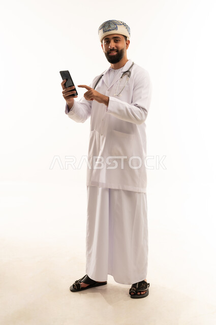 طبيب عماني يحمل هاتف ذكي على خلفية بيضاء