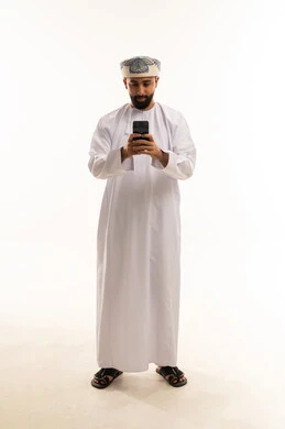 رجل عماني بالزي التقليدي يستخدم الهاتف الذكي في استوديو