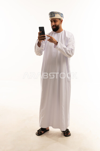 رجل عماني بالزي التقليدي يستخدم الهاتف الذكي