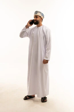 رجل عُماني بالزي التقليدي يتحدث بالهاتف الذكي