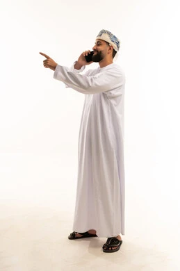 رجل عُماني يتحدث بالهاتف ويشير في استوديو بخلفية بيضاء