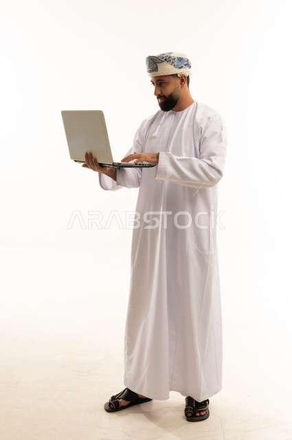 Omani Man in Traditional Dress Using Laptop