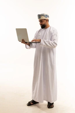 رجل عماني بالزي التقليدي يستخدم كمبيوتر محمول