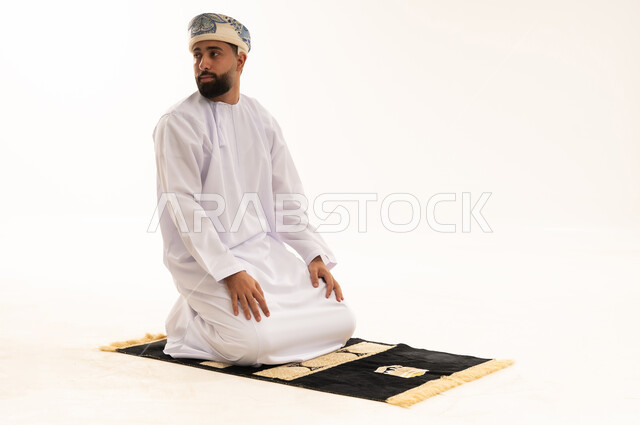 رجل عماني يصلي على سجادة في استوديو أبيض