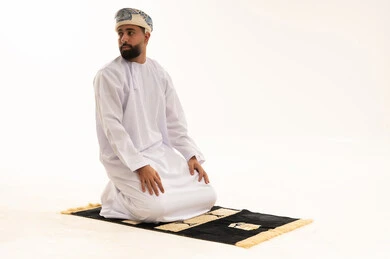 رجل عماني يصلي على سجادة في استوديو أبيض