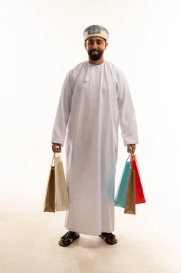 رجل عماني بالزي التقليدي يحمل أكياس تسوق رجل عماني بالزي التقليدي يحمل أكياس تسوق