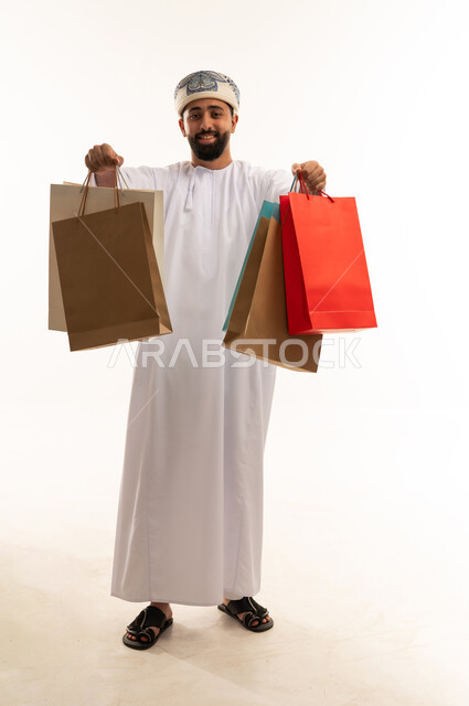 رجل عماني يحمل أكياس تسوق على خلفية بيضاء