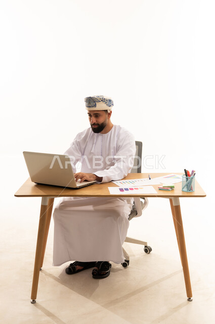 رجل أعمال عماني يعمل على كمبيوتر محمول في المكتب