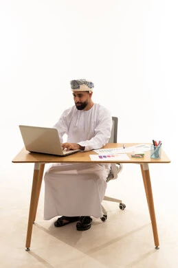 رجل أعمال عماني يعمل على كمبيوتر محمول في المكتب