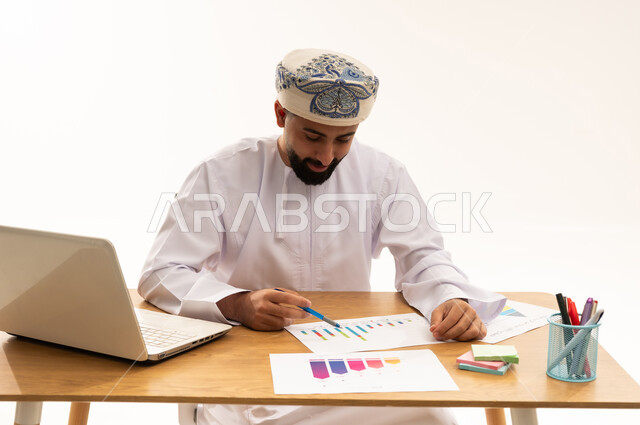 Omani Businessman Analyzing Financial Charts at Desk