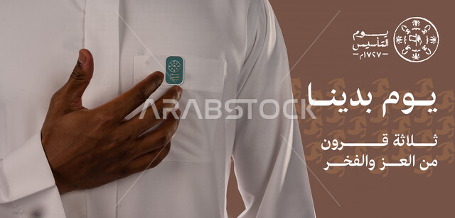 صورة مقربة لرجل عربي خليجي سعودي يقوم بتعليق شعار يوم التأسيس السعودي على صدره، الفخر والإعتزاز، الهوية البصرية ليوم التأسيس السعودي، شعار يوم بدينا، ذكرى تأسيس الدولة السعودية