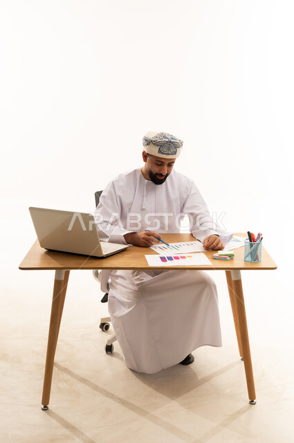 رجل أعمال عماني يحلل الرسوم البيانية على المكتب