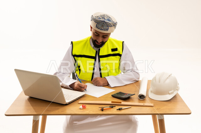 مهندس عماني يعمل على مكتبه مع أدوات هندسية