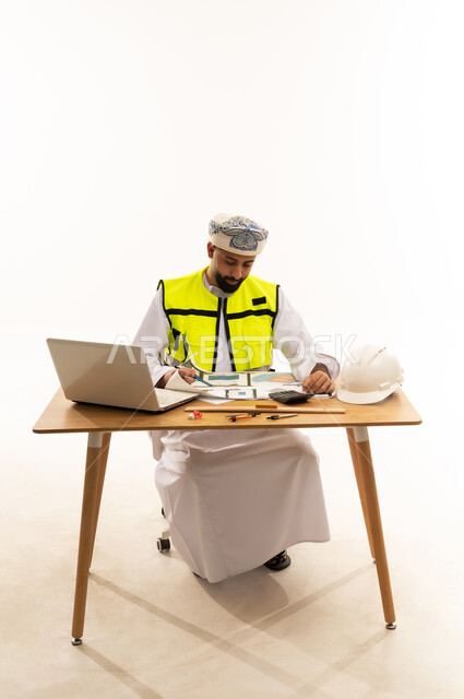 مهندس عماني يراجع مخططات البناء على المكتب