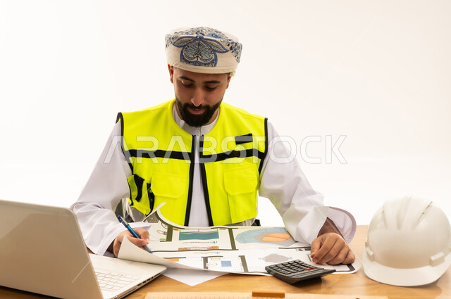 مهندس معماري عماني يراجع مخططات البناء في المكتب