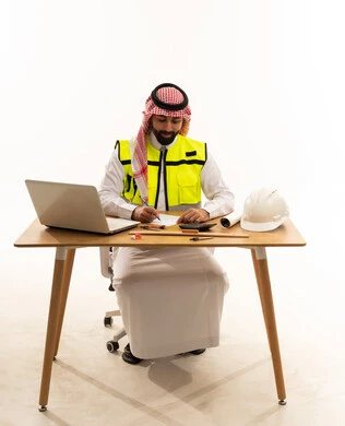 Saudi Engineer Working at Desk with Laptop and Helmet