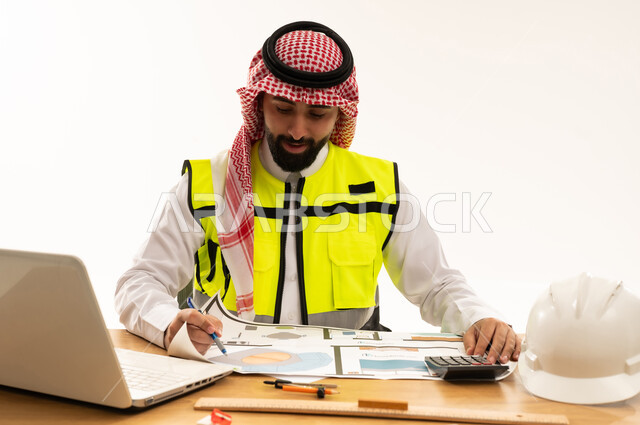 مهندس سعودي يراجع مخططات هندسية على مكتبه