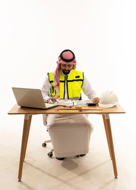 مهندس مدني سعودي يراجع مخططات هندسية على مكتبه