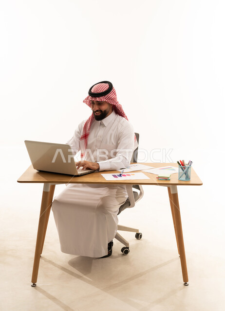 رجل أعمال سعودي يعمل على حاسوب في استوديو