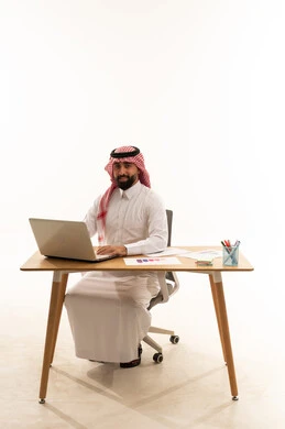 رجل أعمال سعودي يعمل على لابتوب بخلفية بيضاء