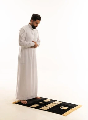 رجل سعودي يصلي على سجادة صلاة بخلفية بيضاء