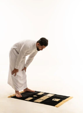 رجل سعودي بالثوب التقليدي يؤدي وضعية الركوع