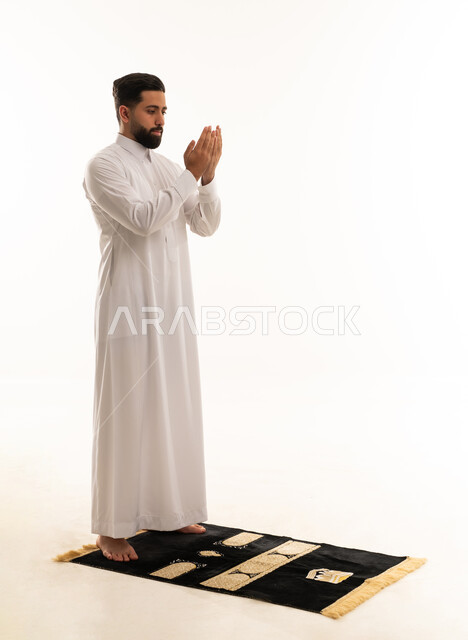 Saudi Man in Thobe Praying on Rug White Background