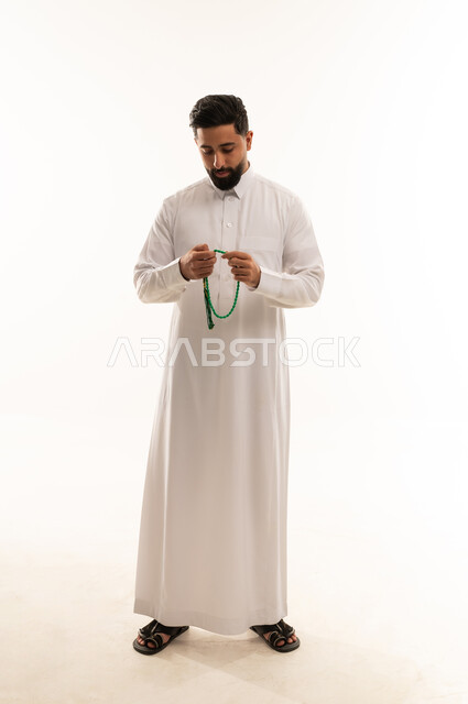 رجل سعودي بالثوب الأبيض يحمل مسبحة خضراء