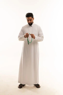 رجل سعودي بالثوب الأبيض يحمل مسبحة خضراء