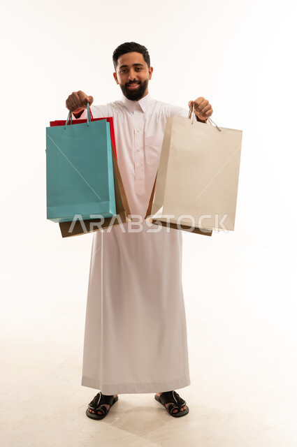رجل سعودي يحمل أكياس تسوق على خلفية بيضاء