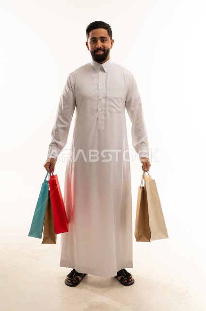 رجل سعودي يحمل حقائب تسوق ملونة في الاستوديو