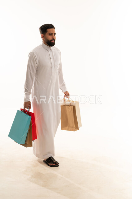 رجل سعودي بالثوب يحمل أكياس تسوق