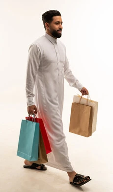 رجل سعودي بالثوب الأبيض يحمل حقائب تسوق