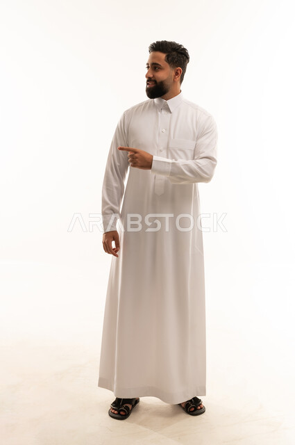 رجل سعودي بالثوب الأبيض يشير على خلفية بيضاء