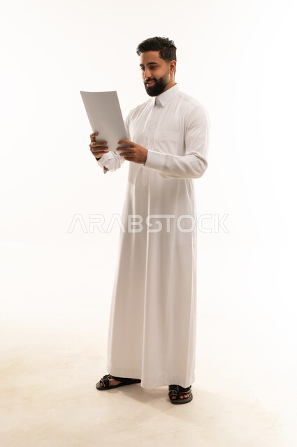 Saudi Man in Thobe Reading Document on White Background