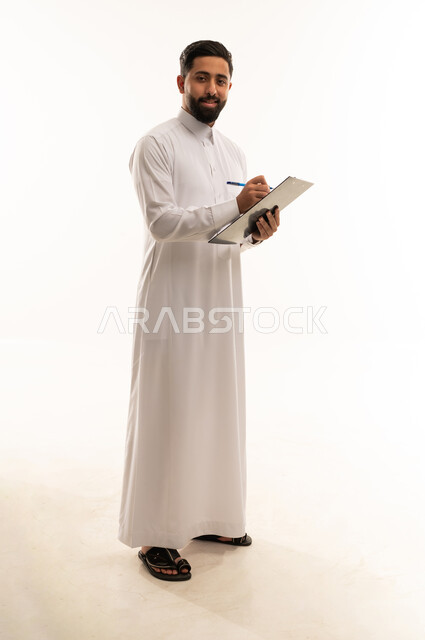 رجل سعودي بالثوب يكتب على لوحة ملاحظات في الاستوديو
