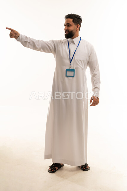 رجل سعودي يرتدي الثوب يشير باتجاه معين أمام خلفية بيضاء