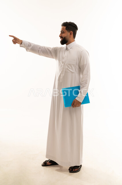 رجل أعمال سعودي يشير بيده مع ملف أزرق