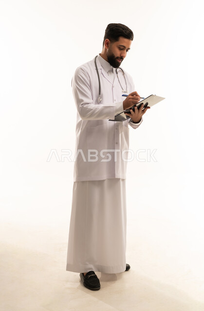 طبيب سعودي بالثوب التقليدي والمعطف الطبي يكتب