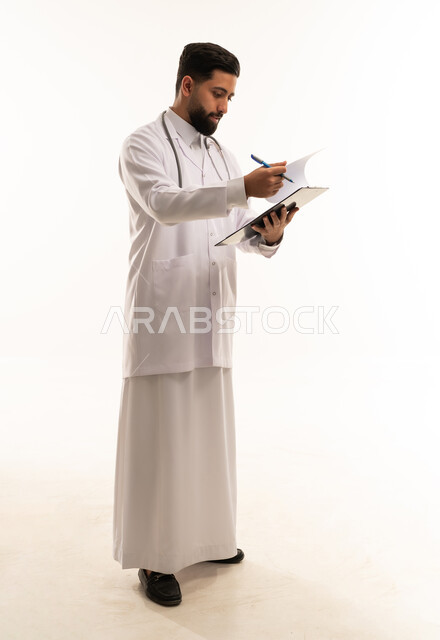 طبيب سعودي يكتب على ملف طبي بالمعطف الأبيض