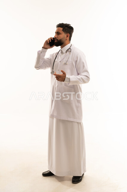 طبيب سعودي يتحدث بالهاتف مرتدياً معطف المختبر الأبيض