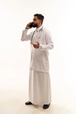 طبيب سعودي يتحدث بالهاتف مرتدياً معطف المختبر الأبيض