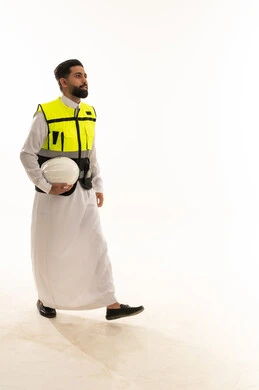 مهندس سعودي بالثوب والسترة يحمل خوذة السلامة