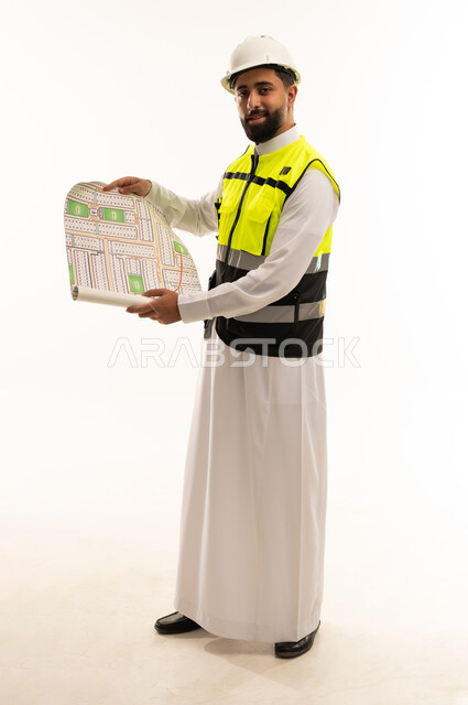 مهندس سعودي يحمل مخطط بناء في استوديو